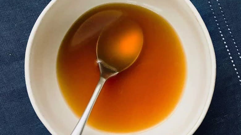 Top-down view of scallop consommé in a bowl with a spoon