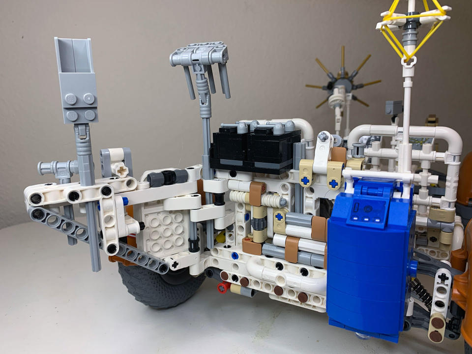 Apollo 17-specific tools, including an adjustable bucket (left), rake (center), seismic explosive charges (black boxes in the middle) and a traverse gravimeter (blue box on the right), are mounted on the rear track of the Lego Technic Apollo Lunar Roving Vehicle.