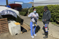 Moira Andrews, a street outreach nurse for Neighborcare Health, speaks with Charles Ussery, 52, who lives in an encampment in the Georgetown neighborhood of Seattle on Monday, April 12, 2021. Andrews spoke with Ussery about the COVID-19 vaccines and answered questions in an effort to vaccinate people experiencing homelessness. Advocates say homeless people are at greater risk of being infected and greater risk of hospitalization and death than the average person, and they should have been prioritized earlier. (AP Photo/Manuel Valdes)