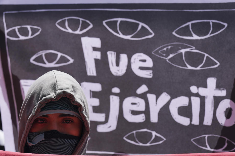 A demonstrator protesting the 2014 disappearance of 43 college students stands in front of a sign with a message that reads in Spanish: "It was the Army" in reference to the missing students, during a protest outside of a military base in Mexico City, Friday, Sept. 23, 2022, days before the anniversary of the disappearance of the students in Iguala, Guerrero in 2014. One week prior, Mexican authorities said they arrested a retired general and three other members of the army for alleged connection to their disappearance. (AP Photo/Fernando Llano)