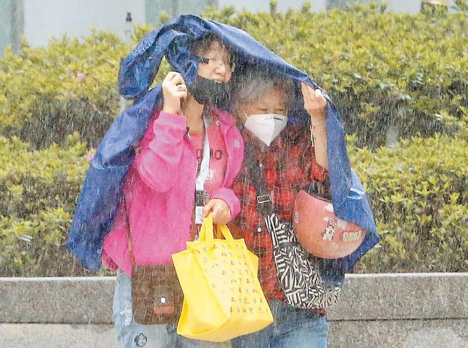 受到鋒面影響，全台天氣相當不穩定，中央氣象署26日針對11縣市發布大雨特報，台北市突然下起的間歇性大雨，讓行人措手不及，拿起衣服遮雨。（趙雙傑攝）