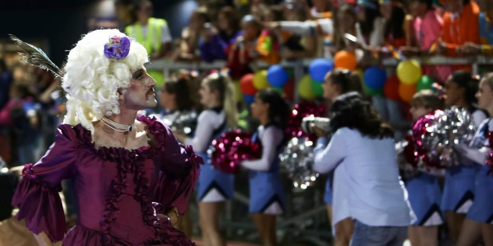 A drag queen walks on the football field.