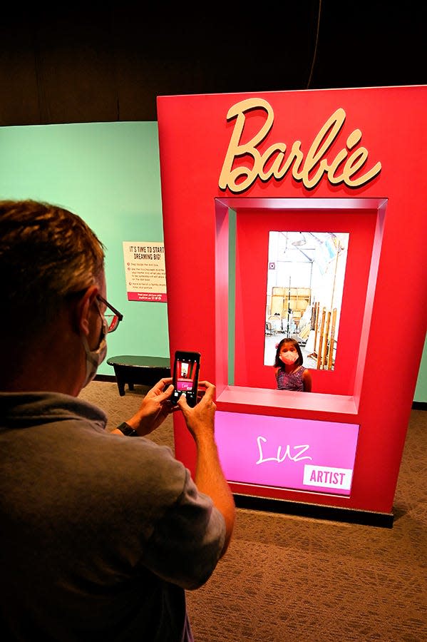 After choosing a career at the "Barbie You Can Be Anything: The Experience" exhibit, young participants can have their photo taken with a backdrop depicting their profession. The exhibit will open at COSI on Oct. 4.