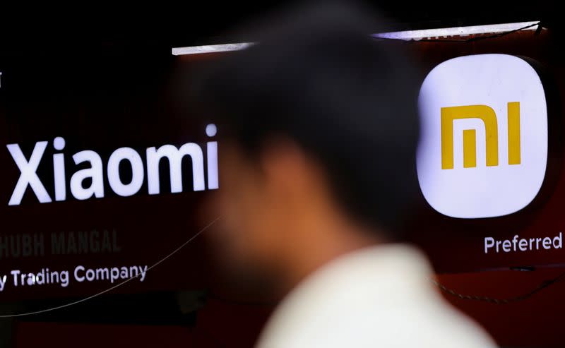 A man walks past a logo of Xiaomi, a Chinese manufacturer of consumer electronics, outside a shop in Mumbai