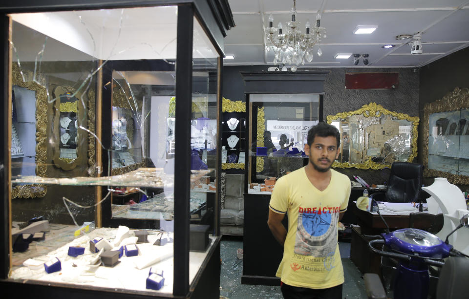 A Sri Lankan Muslim man stands in a vandalized jewelry showroom following overnight clashes with Christians in Poruthota, a village in Negombo, about 35 kilometers North of Colombo, Sri Lanka, Monday, May 6, 2019. Two people have been arrested and an overnight curfew lifted Monday after mobs attacked Muslim-owned shops and some vehicles in a Sri Lankan town where a suicide bombing targeted a Catholic church last month. Residents in the seaside town of Negombo say the mostly-Catholic attackers stoned and vandalized shops. It is unclear how the dispute began but most residents say a private dispute took a religious turn. (AP Photo/Eranga Jayawardena)