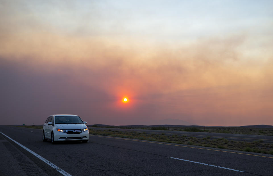 A car rides on the road to Roswell, N.M., as smoke from a wildfire partially blocks the sun near the village of Ruidoso, N.M., Tuesday, June 18, 2024. Thousands of southern New Mexico residents fled the mountainous village as a wind-whipped wildfire tore through homes and other buildings. (AP Photo/Andres Leighton)