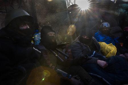 Anti-government protesters huddle under blankets as temperatures stand at minus 20 degrees Celsius (minus 4 degrees Fahrenheit) at a barricade near Independence Square in Kiev, January 30, 2014. REUTERS/Thomas Peter