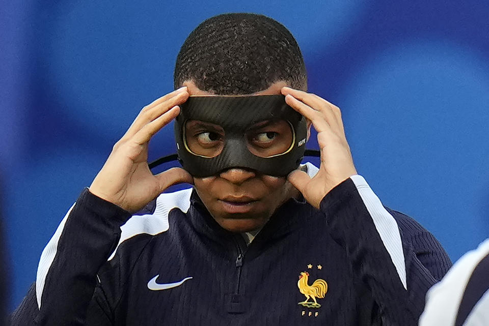 FILE - Kylian Mbappe of France adjusts his face mask as the team warms-up before the Group D match between the Netherlands and France at the Euro 2024 soccer tournament in Leipzig, Germany, on June 21, 2024. Kylian Mbappé has had more masks than goals at Euro 2024. Widely regarded as the heir to Lionel Messi and Cristiano Ronaldo as soccer's biggest icon, the France striker is struggling with his peripheral vision due to the protective face covering he has been fitted with since breaking his nose at the start of the European Championship.(AP Photo/Hassan Ammar)