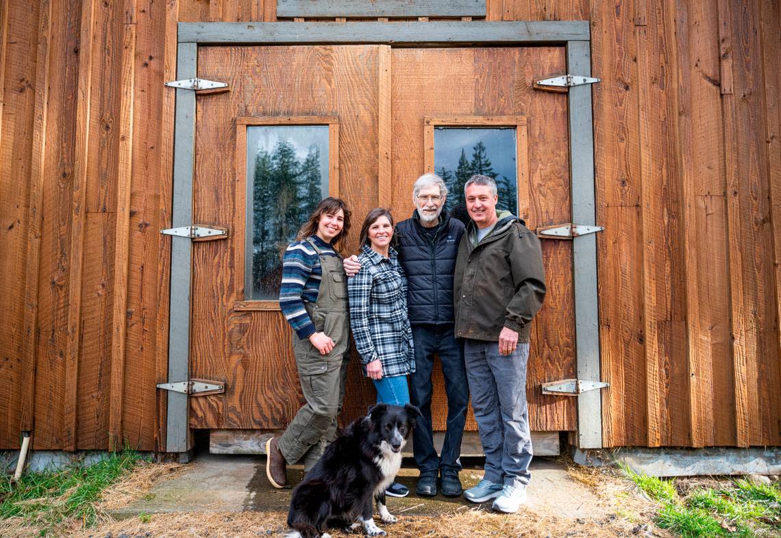 Petra Cole, left, her mother, Sarah Cole, her grandfather, Tom Karlin, and her father, Brad Cole, right, pose for a portrait in front of a barn on their property in Eatonville. on Jan. 5, 2023. Over 60 years ago, Petra’s great-grandparents purchased 40 acres of land where five families including the Cole’s and other relatives now live adjacent to each other on 25 acres of the property.