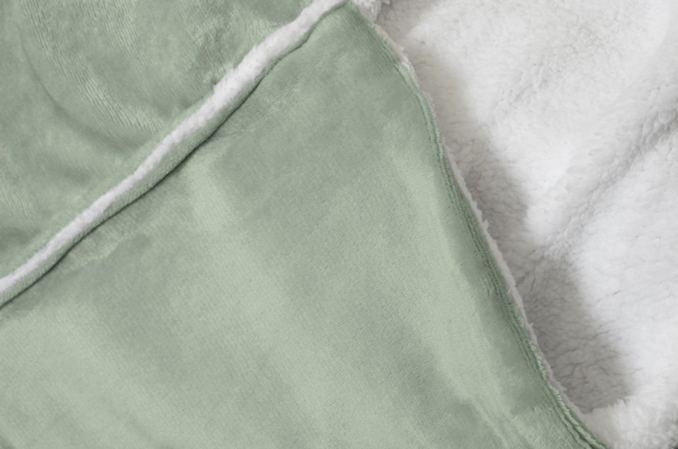 A green blanket with white and warm fleecy sherpa lining on the inner