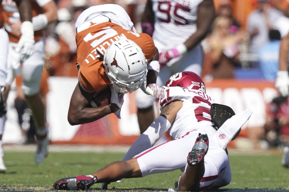 Texas wide receiver Adonai Mitchell (5) is stopped by Oklahoma defensive back Billy Bowman Jr. (2) during the first half of an NCAA college football game at the Cotton Bowl in Dallas, Saturday, Oct. 7, 2023. (AP Photo/LM Otero)