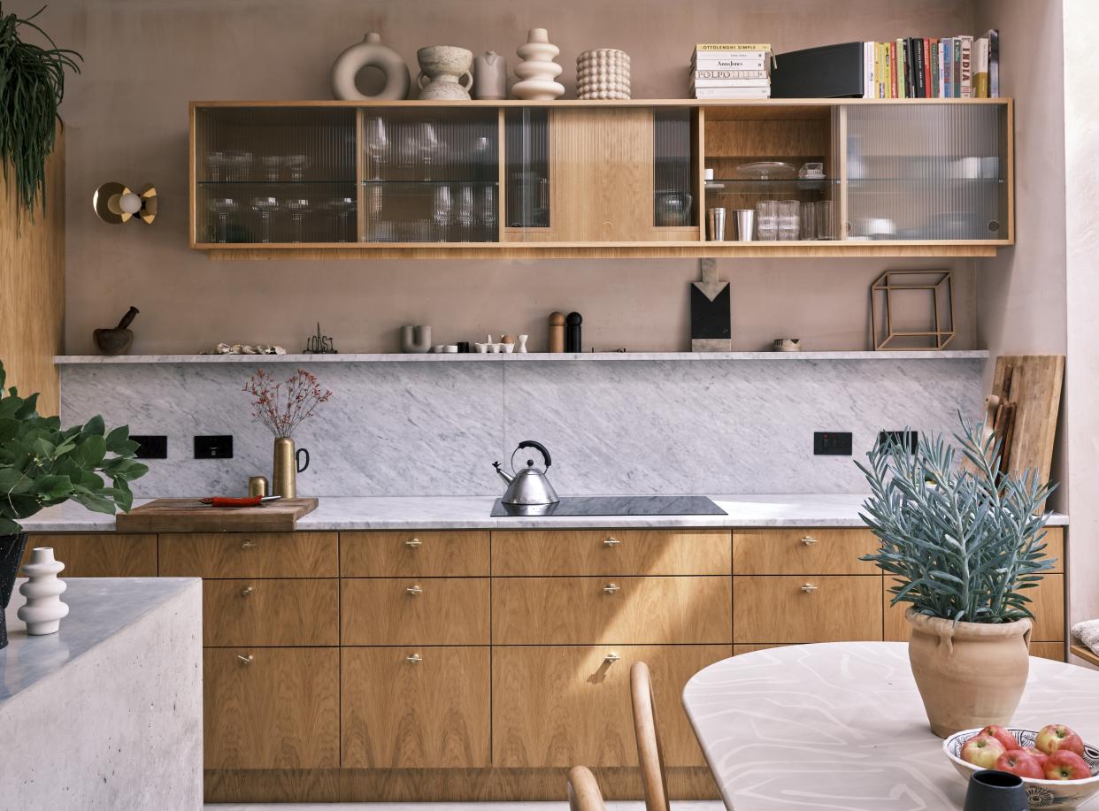  A modern kitchen with wooden cabinetry and stoneware vases displayed on top. 