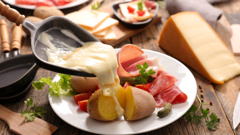 raclette cheese pouring onto potatoes and ham