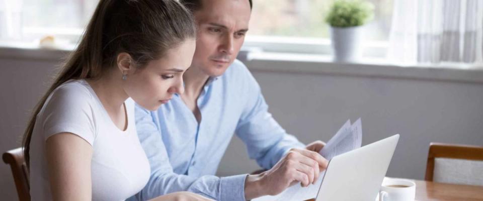 Millennial couple studying mortgage information for new house before signing.