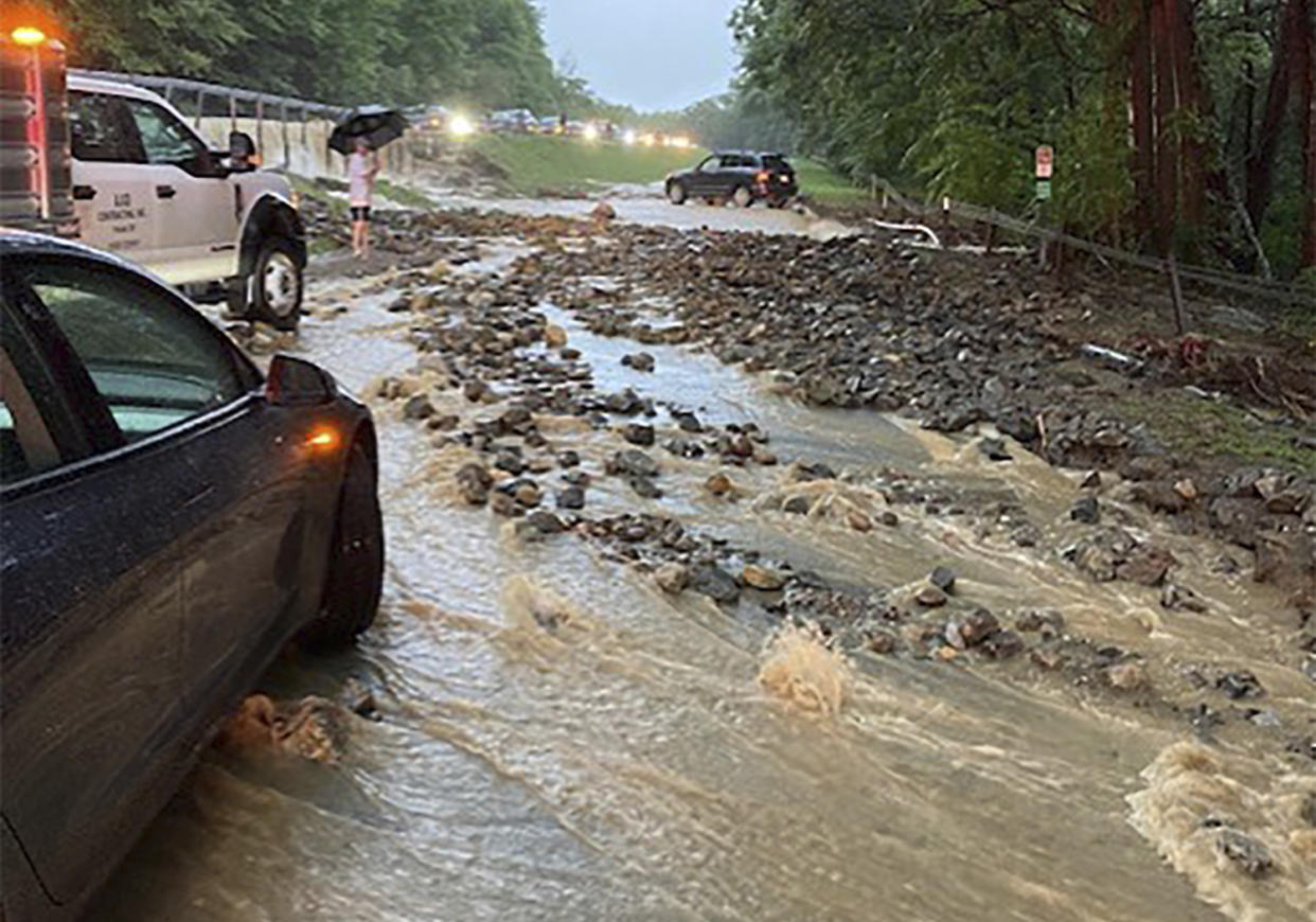 Vehicles at a standstill near a washed-out and flooded portion of the Palisades Interstate Parkway.