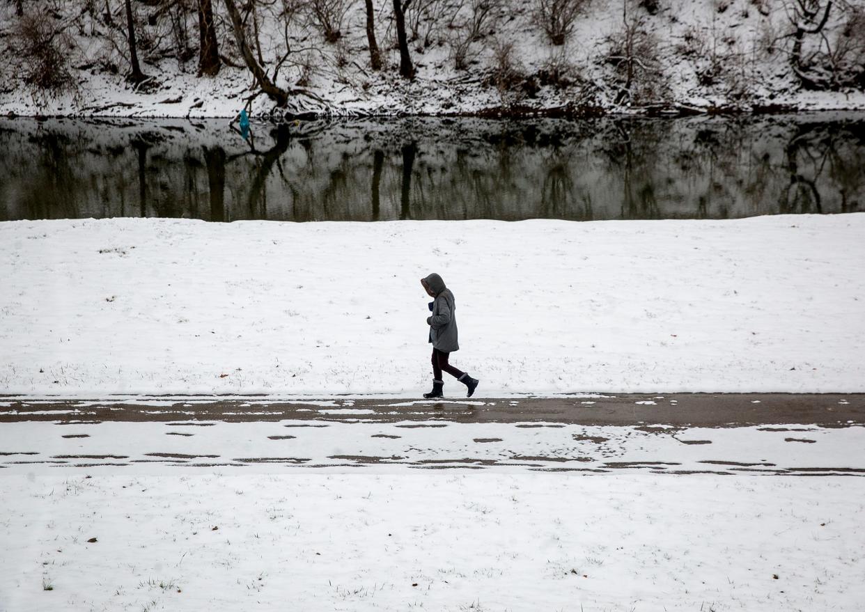 A person walks along the White River near downtown Muncie. 