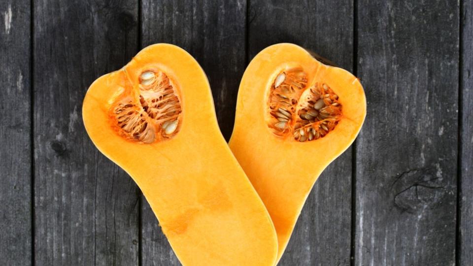 Two halfs of a butternut squash on a old wooden garden table