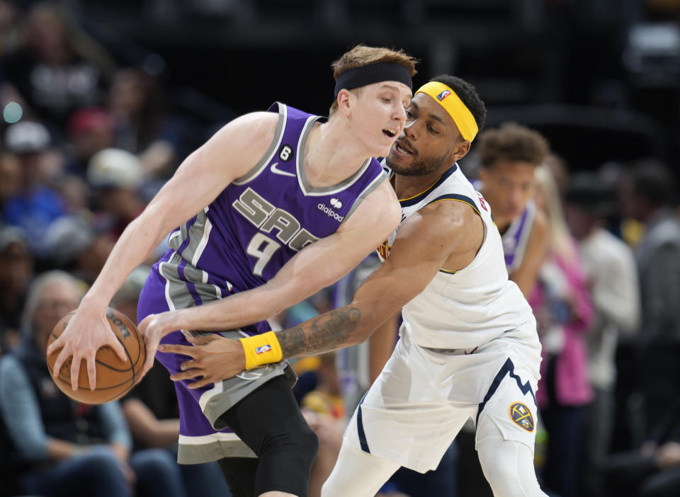 Sacramento Kings guard Kevin Huerter, left, protects the ball as Denver Nuggets forward Bruce Brown defends in the second half of an NBA basketball game, Sunday, April 9, 2023, in Denver. (AP Photo/David Zalubowski)