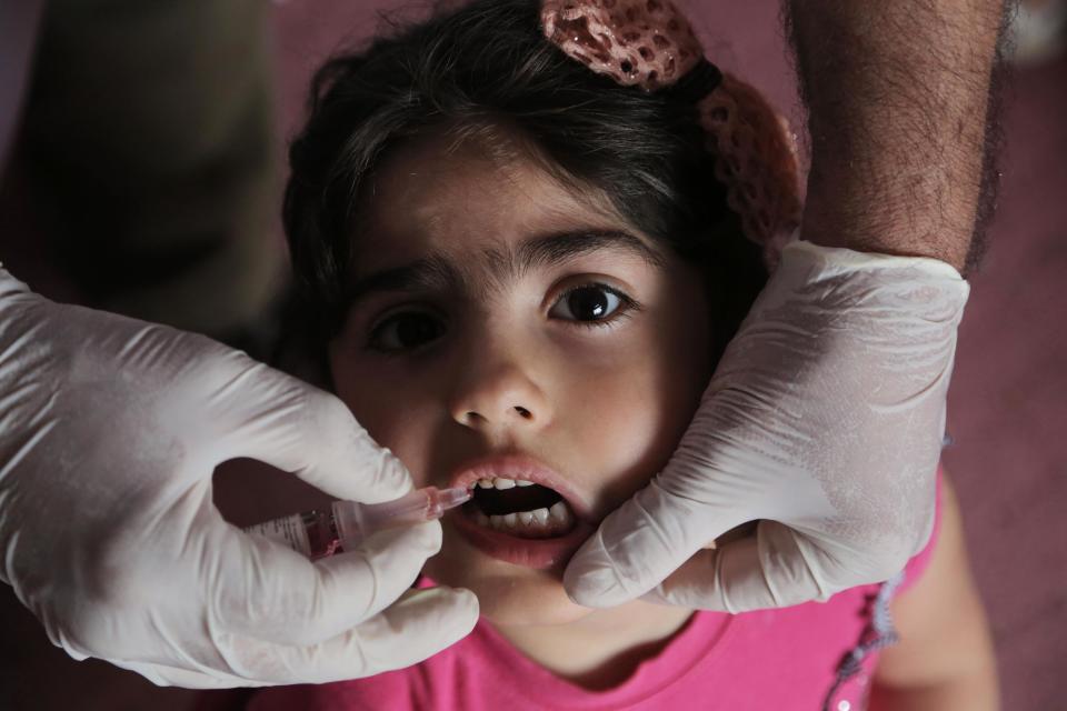 Rose Mohammed, 4, receives a polio vaccine at a kindergarten in Baghdad, Iraq , Thursday, April 10, 2014. With the assistance of international health organizations, Iraqi health officials are scrambling to vaccinate millions of children across Iraq against the highly contagious polio virus in response to the outbreak of the disease in the country as well as the region, a spillover from the three-year-old war in neighboring Syria where handful of children have affected. (AP Photo/Khalid Mohammed)