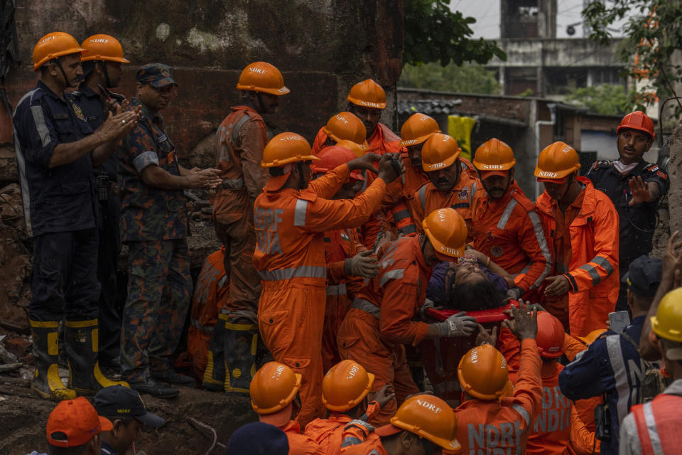 A police officer claps as a woman is rescued from the debris of a four-story residential building that collapsed in Mumbai, India, Tuesday, June 28, 2022. At least three people died and more were injured after the building collapsed late Monday night. (AP Photo/Rafiq Maqbool)