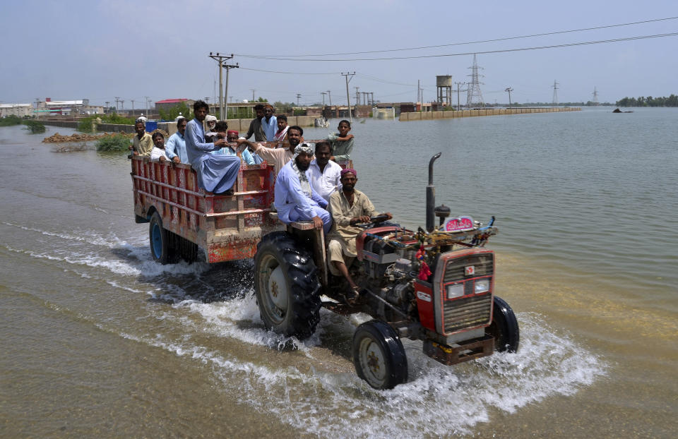 People travel in a trailer pulled by a tractor through a flooded area of Sohbatpur, a district of Pakistan's southwestern Baluchistan province, Monday, Aug. 29, 2022. International aid was reaching Pakistan on Monday, as the military and volunteers desperately tried to evacuate many thousands stranded by widespread flooding driven by "monster monsoons" that have claimed more than 1,000 lives this summer. (AP Photo/Zahid Hussain)