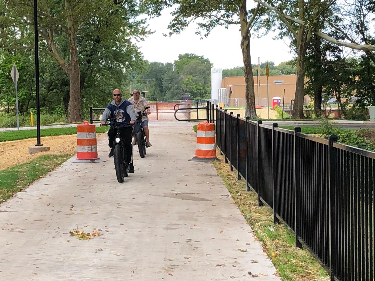 Cyclists ride the newly paved portion of South Bend's Coal Line Trail with the unfinished pedestrian bridge over the St. Joseph River behind them in September 2023.