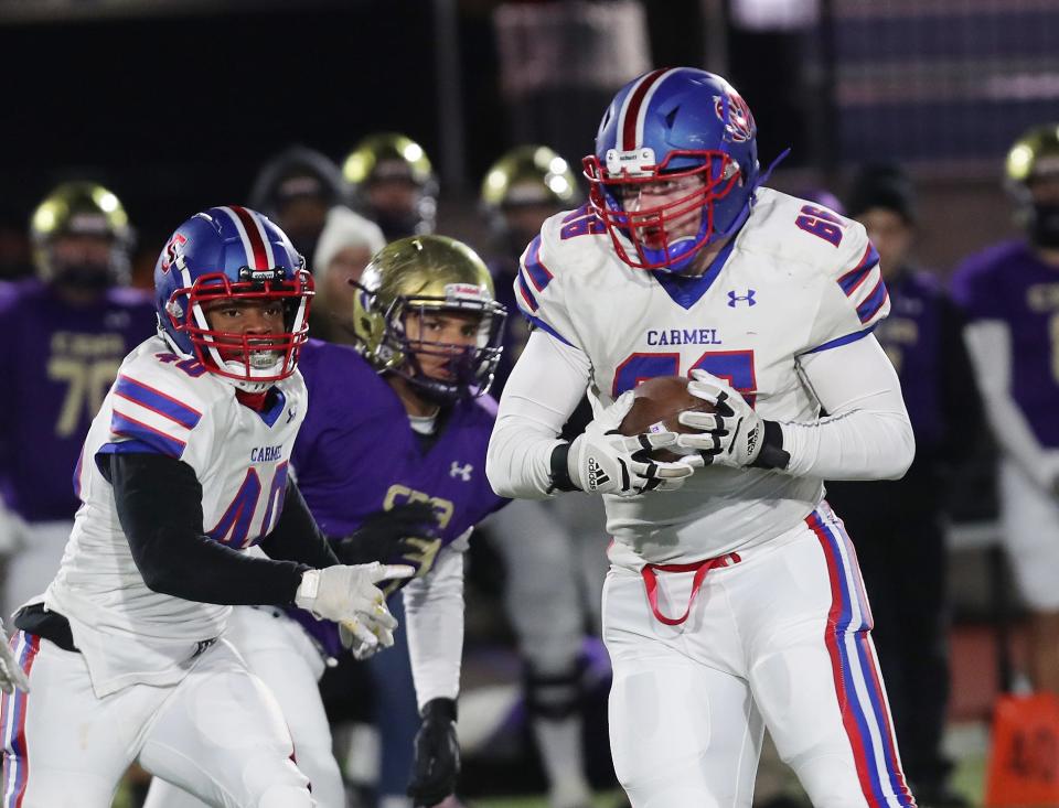 Carmel's Liam Forster (66) intercepts a Christian Brothers Academy pass and returns it for a touchdown during the Class AA state semifinal playoff game at Middletown High School Nov. 25, 2023.