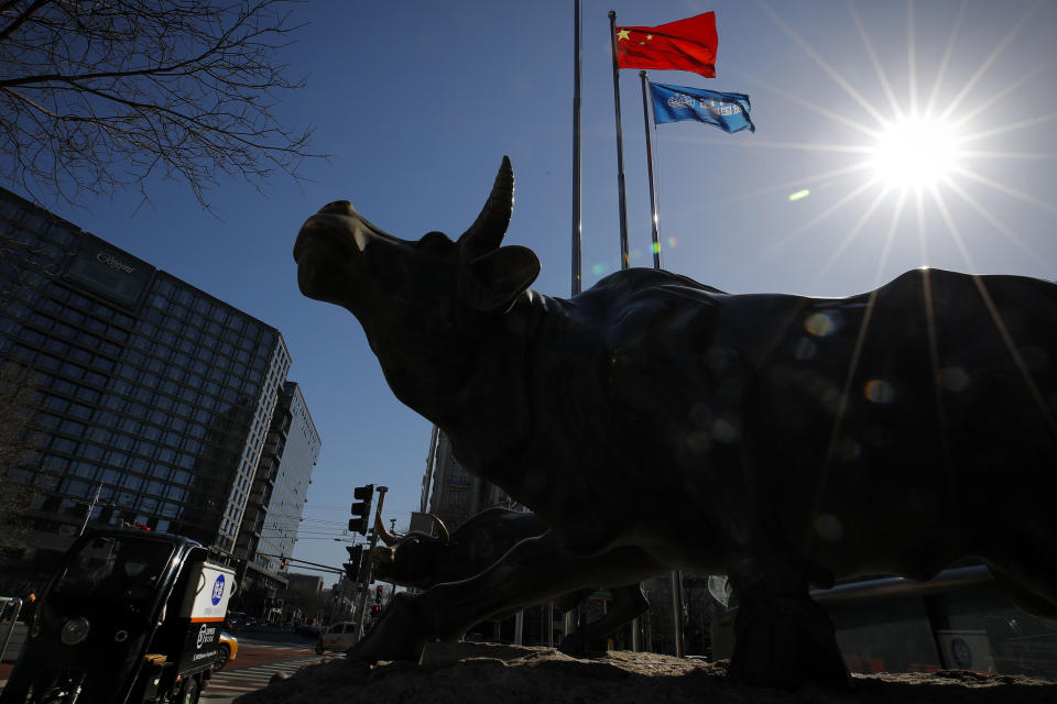 A delivery worker ride his cart passes by the investment icon bull statue on display outside a bank in Beijing, Tuesday, March 10, 2020. Asian stock markets are taking a breather from recent declines. Several benchmarks gained more than 1% on Tuesday after New York futures reversed on news that President Donald Trump plans to ask Congress for a tax cut and other quick measures to ease the pain of the virus outbreak. (AP Photo/Andy Wong)