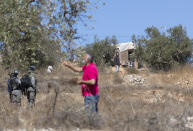 A Palestinian man harvests olives near a Jewish settlers outpost, seen in the background, in the West Bank village of Burqa, East of Ramallah, Friday, Oct. 16, 2020. Palestinians clashed with Israeli border police in the West Bank on Friday during their attempt to reach and harvest their olive groves near a Jewish settlers outpost. (AP Photo/Nasser Nasser)