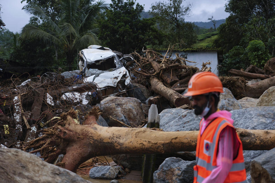 Un rescatista pasa por delante de árboles arrancados, un auto dañado y otros escombros en el segundo día de trabajos tras los deslaves registrados en Chooralmala, en el distrito de Wayanad, en el estado de Kerala, India, el 31 de julio de 2024. (AP Foto/Rafiq Maqbool)