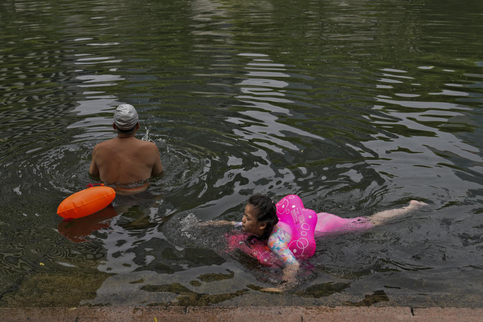 Residents swim at an urban waterway to cool off from an unseasonably hot day in Beijing, Monday, July 3, 2023. Heavy flooding has displaced thousands of people around China as the capital had a brief respite from sweltering heat. Beijing reported 9.8 straight days when the temperature exceeded 35 C (95 F), the National Climate Center said Monday. (AP Photo/Andy Wong)