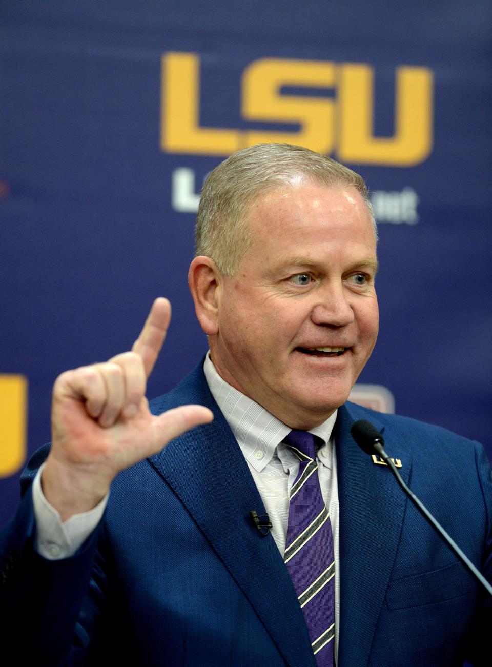 Newly named LSU Tigers head football coach Brian Kelly gives the "L" sign for LSU as he answers media questions after being introduced in a press conference at Tiger Stadium on Dec. 1, 2021.