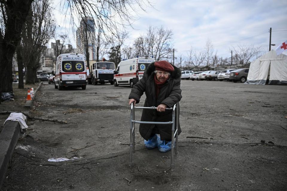 An elderly woman leans on her walker as she stands outside a destroyed apartment building following shelling in the northwestern Obolon district of Kyiv (AFP/Getty)