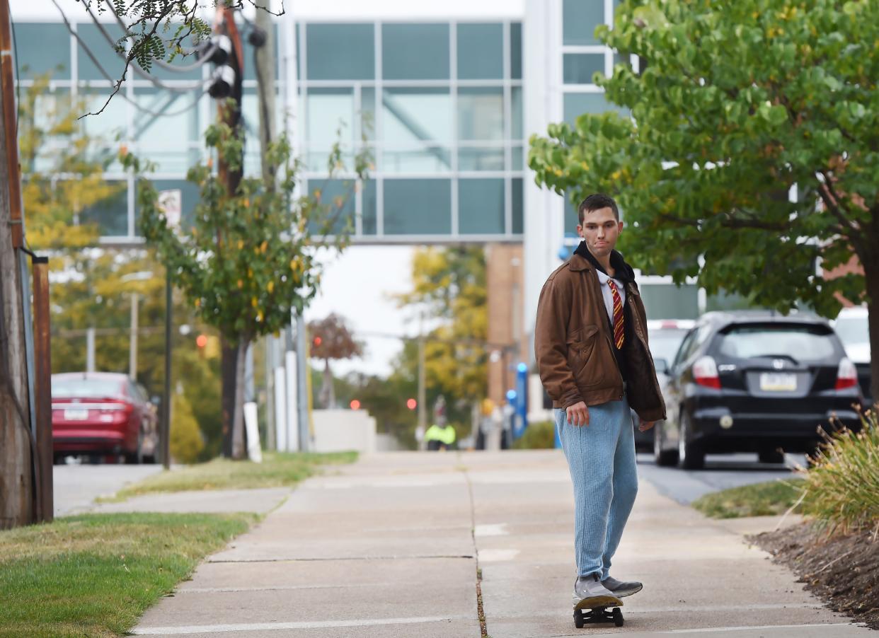 Michael Richardson, 23, rides his skateboard east along East Seventh Street near the Erie Insurance campus, background, in Erie on Oct. 9. Richardson may soon have more competition on nearby sidewalks as Erie Insurance employees are being asked to return to the office in greater numbers