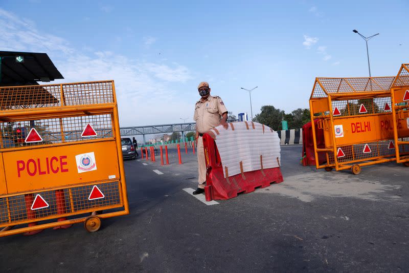 A police officer stands at New Delhi's border barricade during lockdown by the authorities to limit the spreading of coronavirus disease (COVID-19), in New Delhi