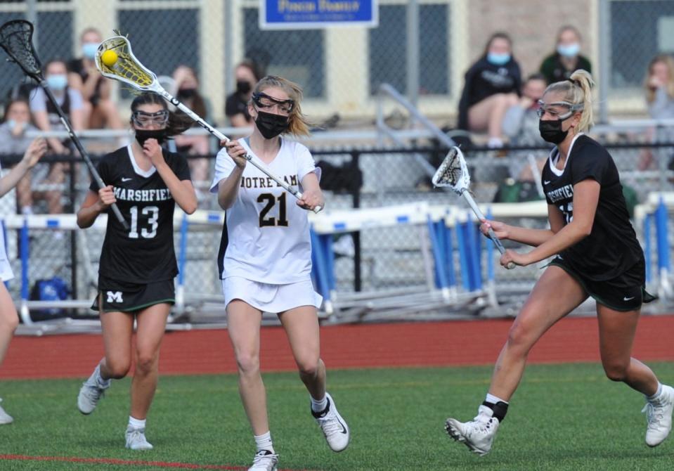 Notre Dame Academy's Reilly Walsh of Walpole, center, prepares to pass as Marshfield defenders Kaitlin O'Brien, left, and Charlotte Reynolds, right, move in during girls high school lacrosse at Notre Dame Academy in Hingham, Thursday, May 13, 2021.