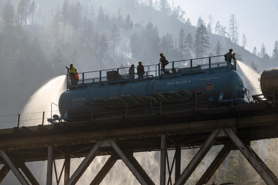 Firefighters spray water from Union Pacific Railroad's fire train while battling the Dixie Fire in Plumas National Forest, Calif., on Friday, July 16, 2021. (AP Photo/Noah Berger)