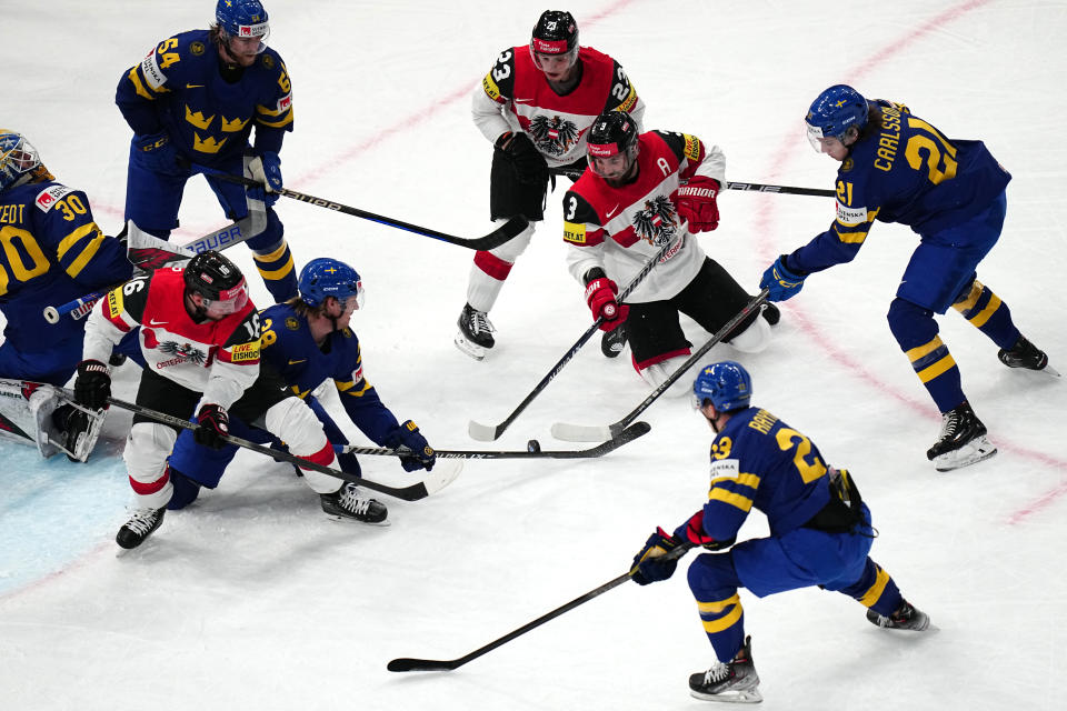 Players battle for the puck during the group A match between Sweden and Austria at the ice hockey world championship in Tampere, Finland, Sunday, May 14, 2023. (AP Photo/Pavel Golovkin)