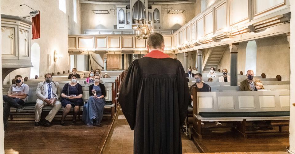 Priest Matthias Hieber celebrates a confirmation service according to the Corona protection measures in the church in Suesel, Germany, Sunday, July 12, 2020. Distance on the church pews, wearing of mouth and nose masks and silence during the service. Only the pastor is allowed to speak and to pray. (Markus Scholz/dpa/dpa via AP)