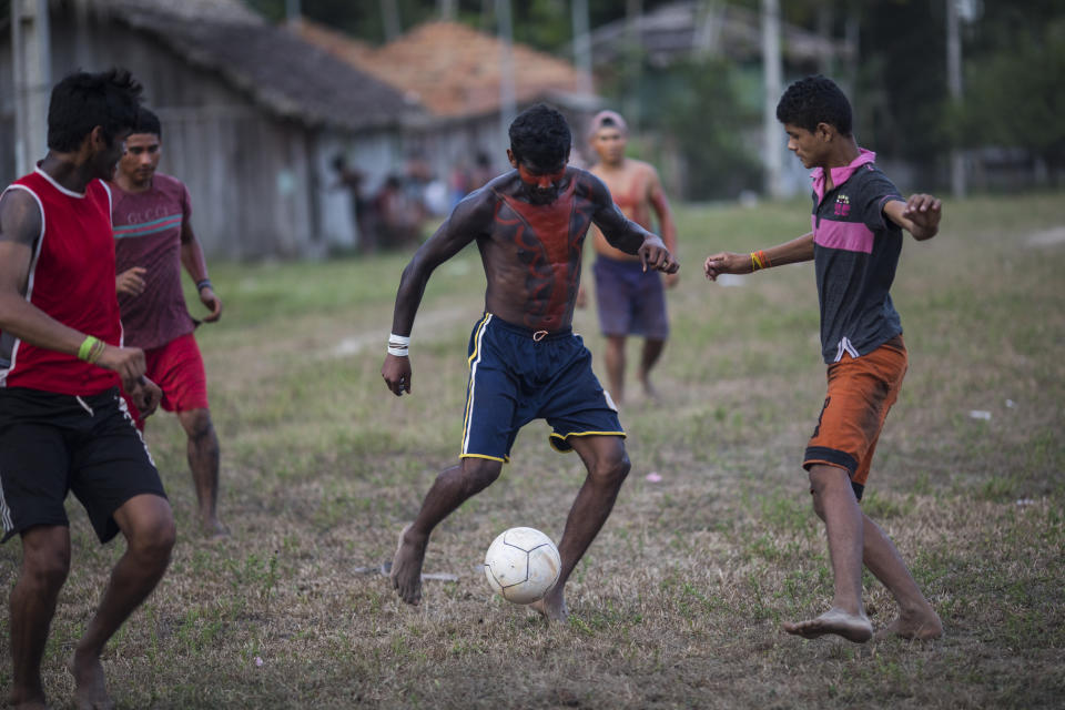 In this Sept. 3, 2019 photo, villagers in traditional indigenous body paint play soccer after a meeting of Tembé tribes at the Tekohaw indigenous reserve, Para state, Brazil. Some of the men wear a type of red face paint that signifies they are ready for war. Recent clashes saw the Tembe burning the trucks and equipment of illegal loggers on their territory, which is located in a Brazilian state plagued by thousands of fires burning on cleared jungle lands. (AP Photo/Rodrigo Abd)