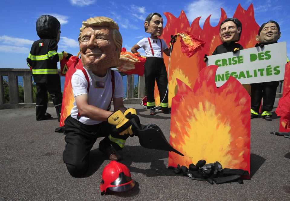 A man wearing a mask President Donald Trump is joined by other 'world leaders' during a protest ahead of the G-7 summit in Biarritz, France Friday, Aug. 23, 2019. The European Union and Germany are backing French President Emmanuel Macron's call to put the Amazon fires on the agenda of this weekend's G-7 summit of world leaders in France. Other leaders are from left: Italian Premier Giuseppe Conte, French President Emmanuel Macron, Canadian Prime Minister Justin Trudeau and Japanese Prime Minister Shinzo Abe. (AP Photo/Peter Dejong)