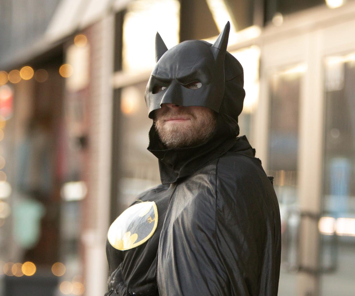Batman looks to passing traffic on downtown Brighton's Main Street Friday, Jan. 21, 2022. He strolls up and down the business district greeting customers and passers-by.