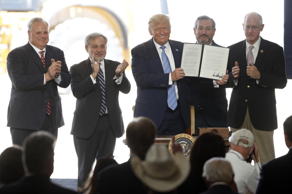 President Donald Trump holds up a permit for energy development after signing it during a visit to the Double Eagle Energy Oil Rig, Wednesday, July 29, 2020, in Midland, Texas. Sen. Ted Cruz, R-Texas, stands rear, second from right. (AP Photo/Tony Gutierrez)