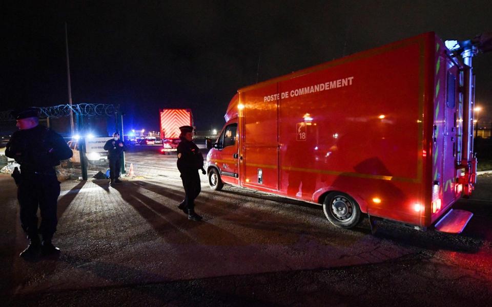 Police officers stand next to a fire command centre arriving at Calais after at least 30 migrants died when their boat sank