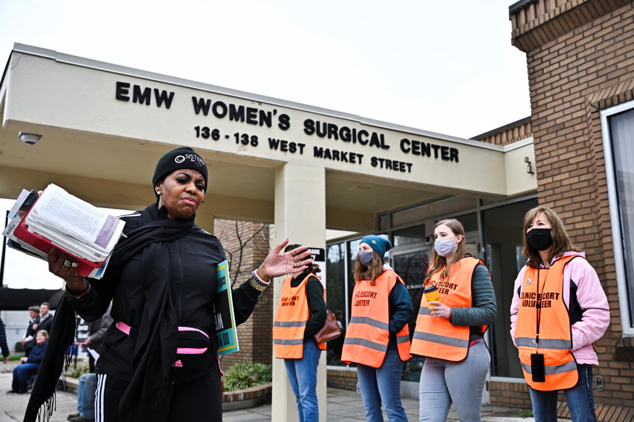 An anti-abortion protester recites a Bible passage while clinic escorts stand nearby at the EMW Women's Surgical Center in Louisville days after the Kentucky state legislature enacted a sweeping anti-abortion law, on April 16.