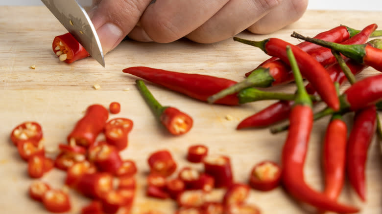 person slicing red chile peppers