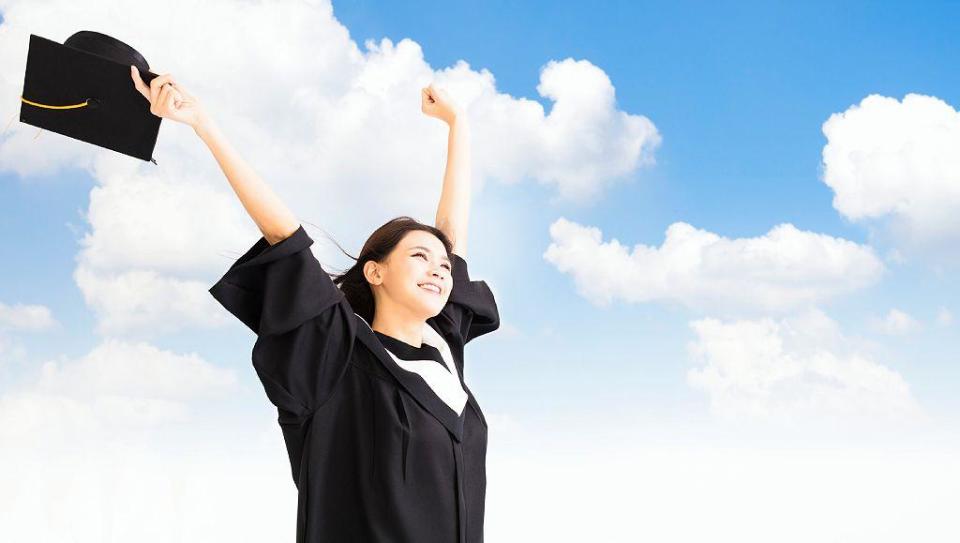 Chica vestida de graduada con manos levantadas y feliz