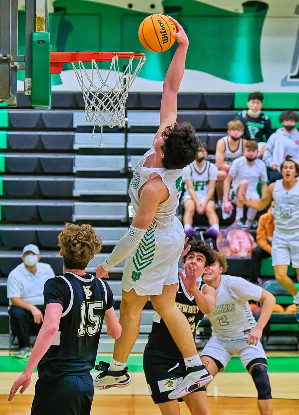 Caleb Chin soars for a dunk during Thousand Oaks' win over Newbury Park on Jan. 18. After missing most of the team's first 16 games, the 6-foot-5 Chin has returned to help the Lancers solidify their hold on first place in the Marmonte League.