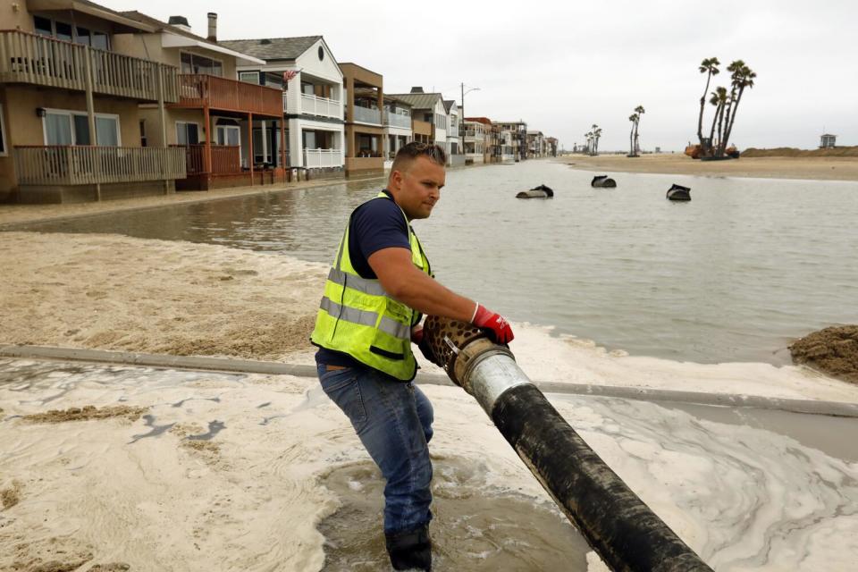 Jack Corrigan lifts pumping tubes into places to elevate some of the flooding caused by high tides.