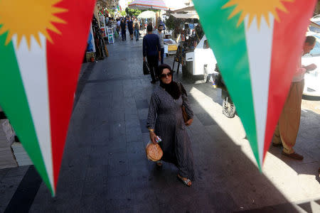 A woman walks on the street, between banners supporting the referendum for independence of Kurdistan in Erbil, Iraq September 24, 2017. REUTERS/Alaa Al-Marjani